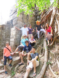 Students posing for a photo by roots around a Cambodian cultural site