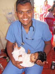 Student doctor holding an infant during a Mercer On Mission Cambodia trip