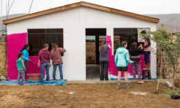 Students painting the front of a house pink