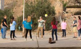 Students standing in a circle playing a game with a ball