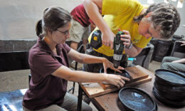 Students drilling holes in a shallow pan