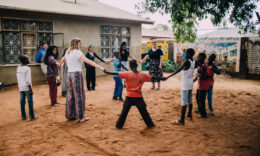 Mercer students standing in a circle with children during a Mercer On Mission Tanzania trip