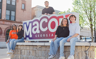 Students posing in front of Macon sign downtown