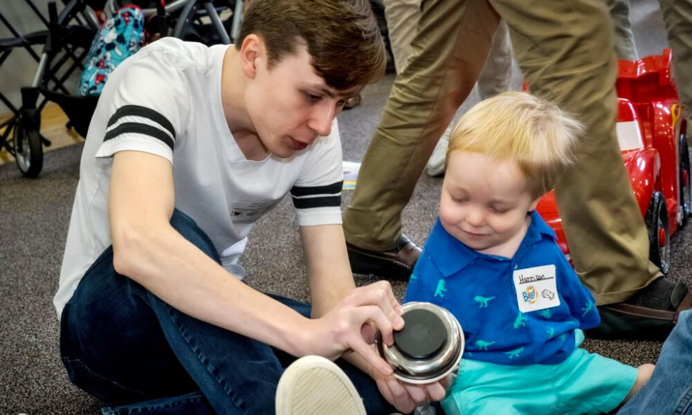 Student sitting with a disabled child showing him how a machine part is working