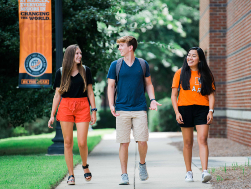 Three students walking together on a sidewalk