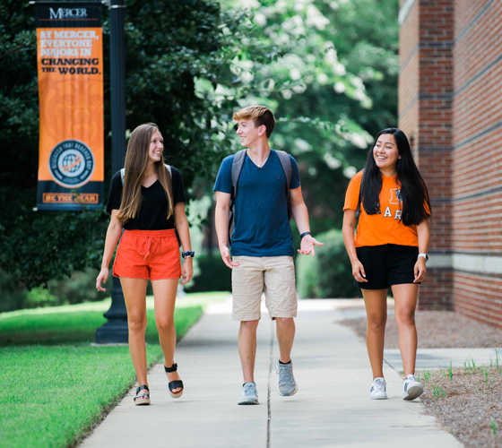 Three students walking together on a sidewalk