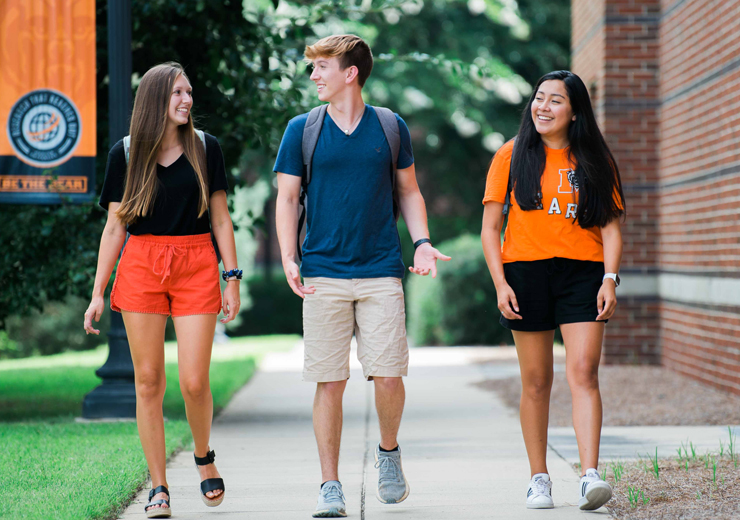 Three students walking on a sidewalk together