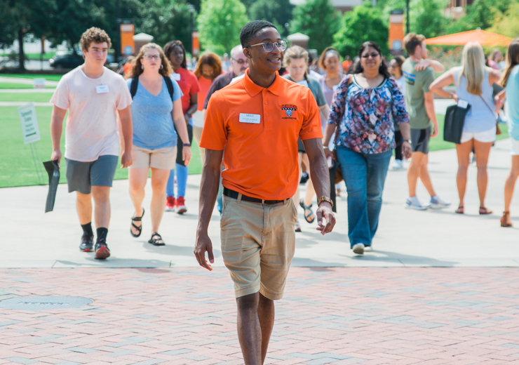 Student admissions worker leading a tour for prospective students and their families