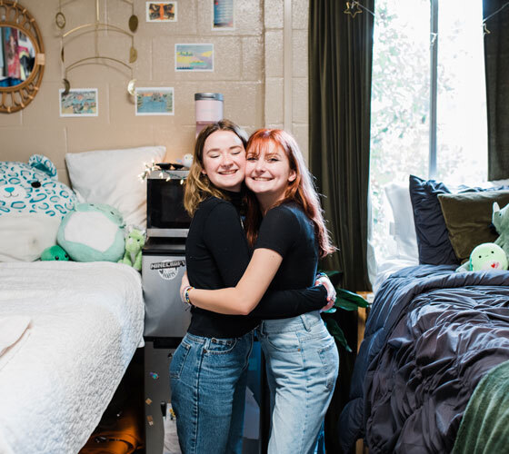 Two roommates hugging in their dorm room