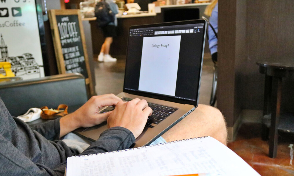 Student sitting in a coffee shop working on an essay