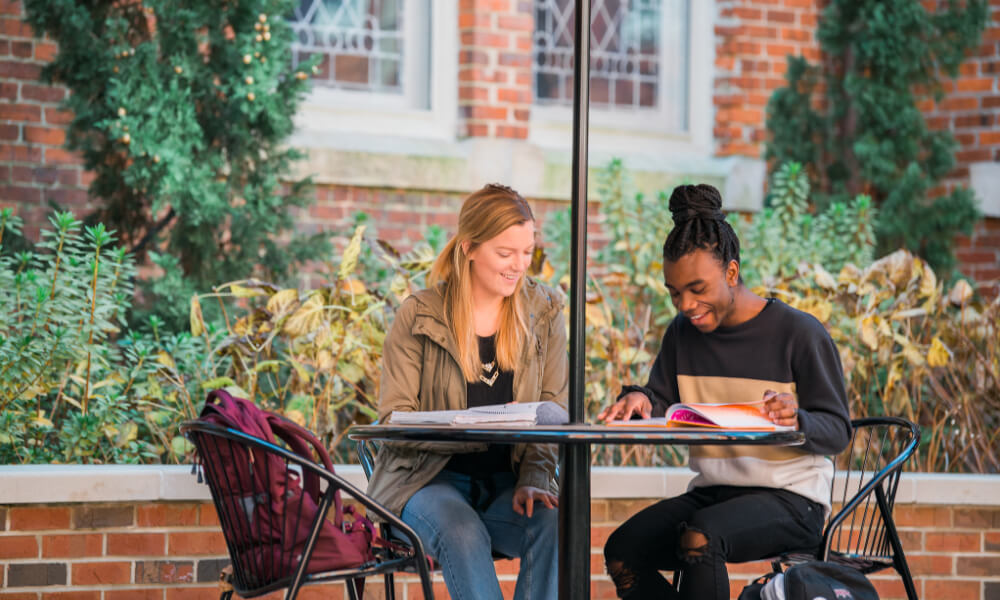 Two students studying at a table outside