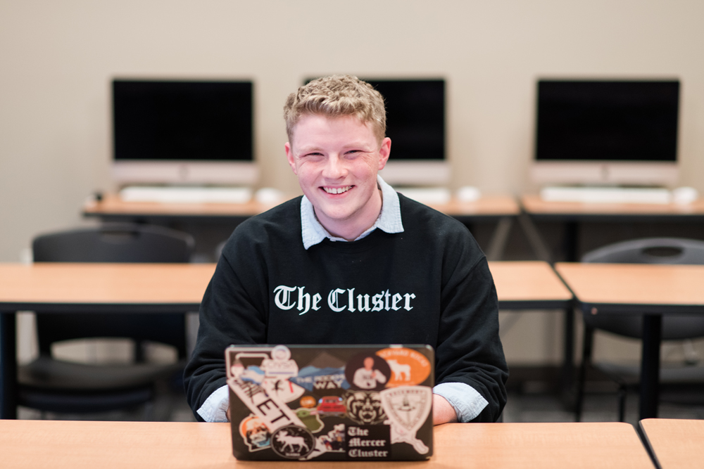Journalism student working on his laptop while smiling