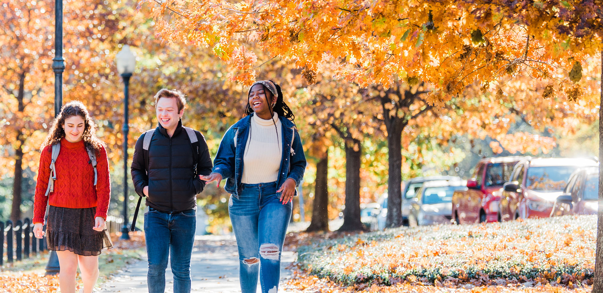 Three students walking on campus in the fall