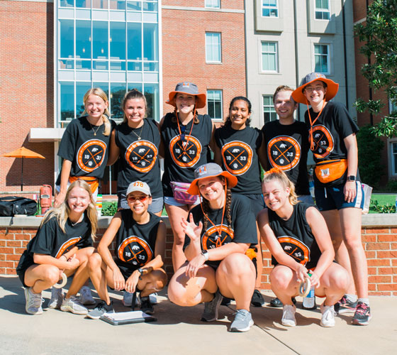 Student volunteers posing for a photo in front of legacy hall on move in day