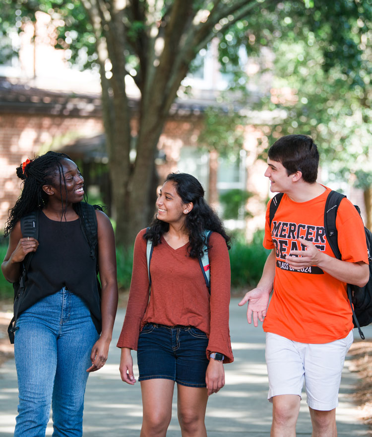 Three students talking while walking on campus