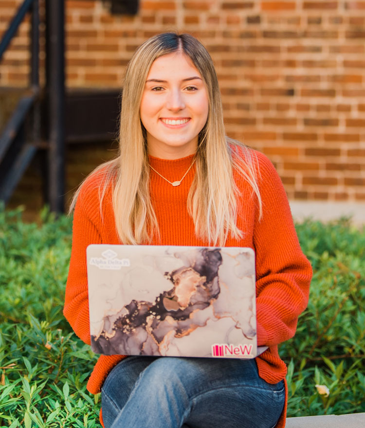 Student smiling at camera while on computer