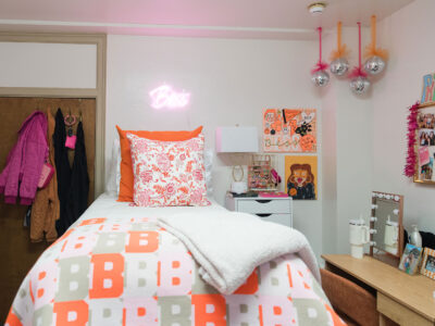 A bedroom in Mary Erin Porter with a neon sign above the bed and mini disco balls hanging from the ceiling.
