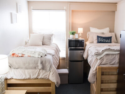 A color-coordinated bedroom in Plunkett Hall with a mini fridge and microwave between beds.