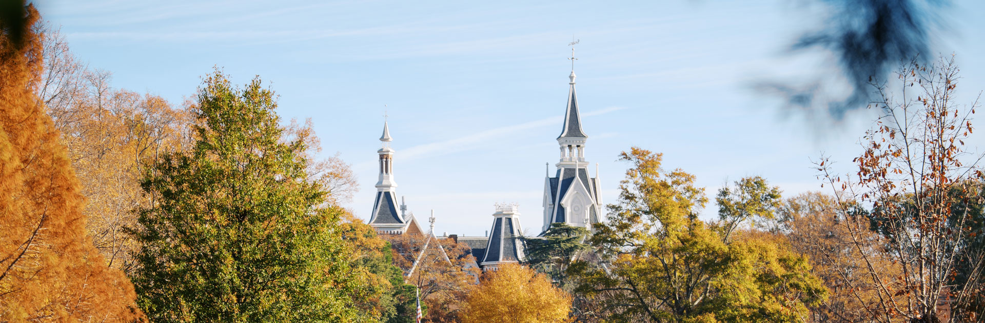 A skyline including fall-colored trees and the spires of the Godsey Administration Building