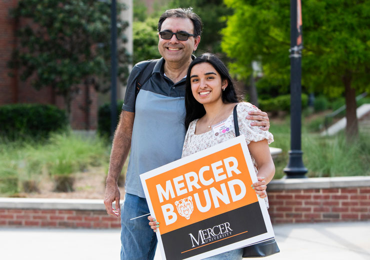 A father and daughter smiling with her MercerBound sign at an admissions event