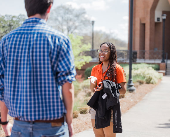 A student tour guide talking to a prospective student during a campus tour